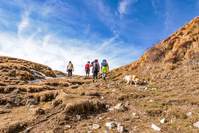 Low angle view of people hiking on mountain against sky