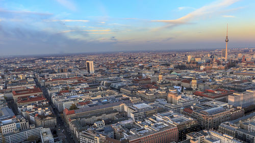 Fernsehturm amidst cityscape against sky during sunset