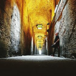 Woman walking in illuminated tunnel