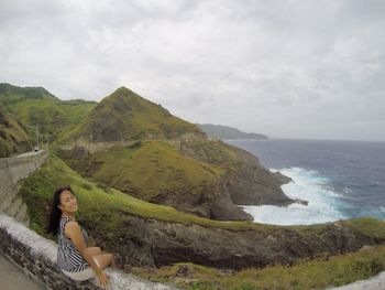 Woman standing on mountain by sea against sky