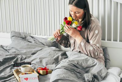 Midsection of woman sitting on bed