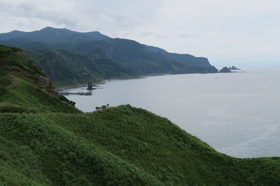 Scenic view of sea and mountains against sky