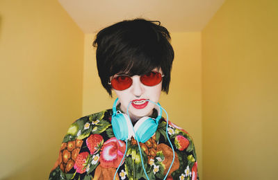 Portrait of woman wearing sunglasses against colored background