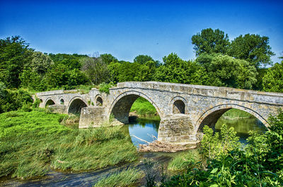Arch bridge over river against blue sky