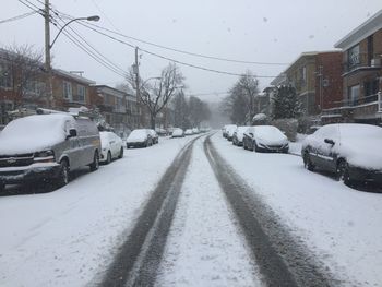 Cars on snow covered road against sky