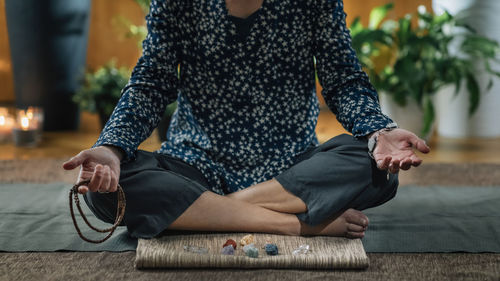 Low section of woman meditating at home