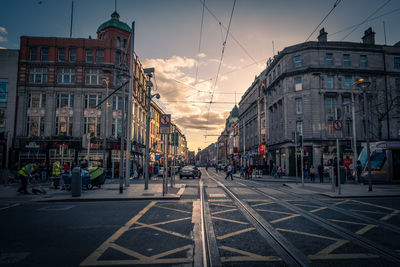 City street and buildings against sky during sunset