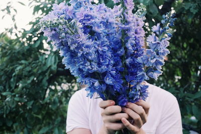 Woman holding flowers while standing in park