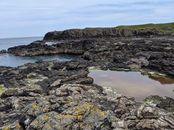 Rock formation on beach against sky