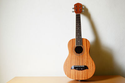 Close-up of acoustic guitar against wall