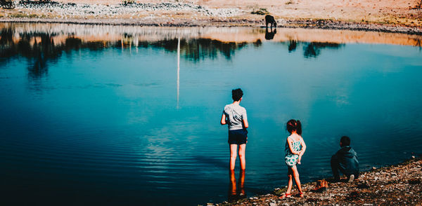 Rear view of people standing in lake