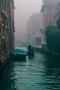 Boats in canal amidst buildings in city