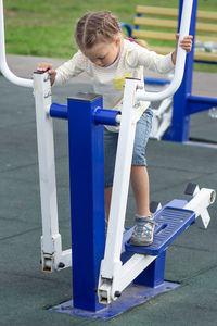 Caucasian little girl child kid of 5 years making exercises on step equipment outdoors