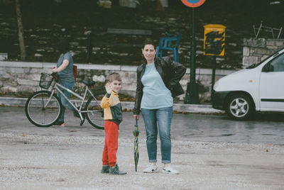 Full length of woman standing with son on road