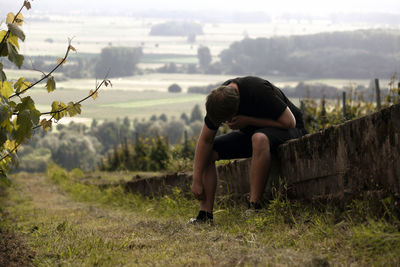 Man sitting by vineyard