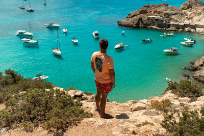 Rear view of man on rocks by sea