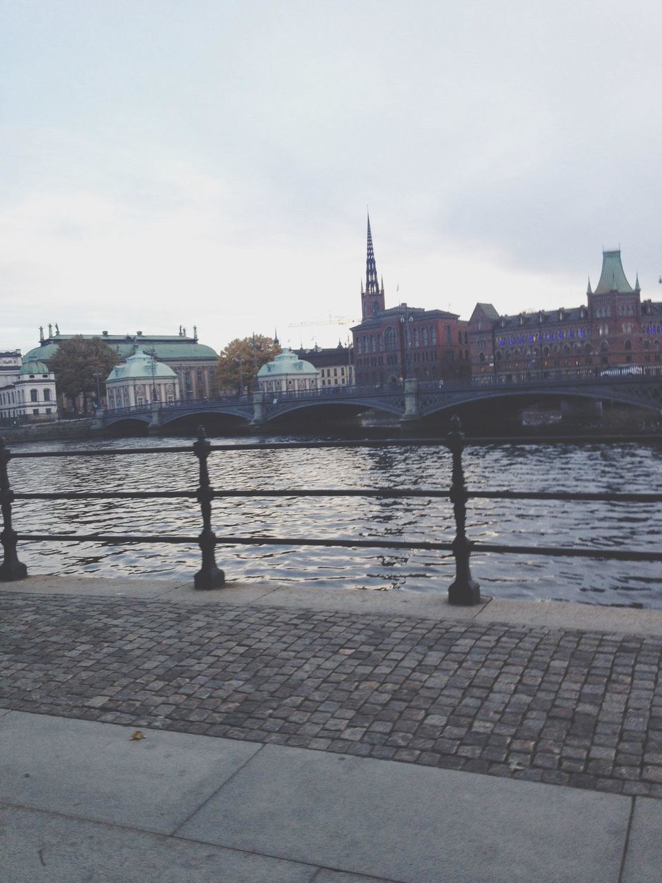 architecture, built structure, building exterior, water, river, sky, bridge - man made structure, city, connection, transportation, canal, railing, day, travel destinations, bridge, outdoors, waterfront, cloud - sky, nautical vessel, no people