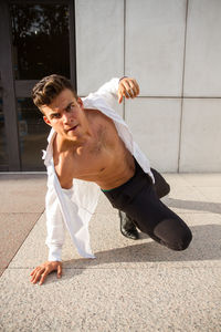 Portrait of young man on street against wall