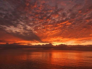 Scenic view of sea against dramatic sky during sunset