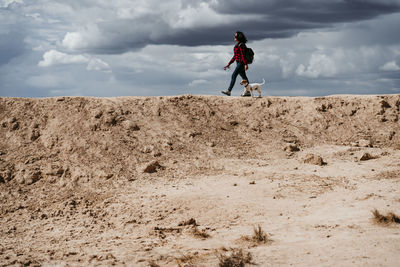 Spain, navarre, young woman hiking with dog in bardenas reales