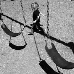 High angle view of boy walking by swing at playground