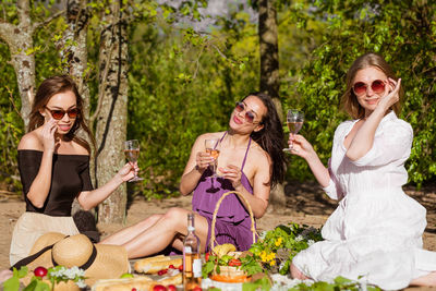 Cheerful women are resting in nature with wine. beautiful
