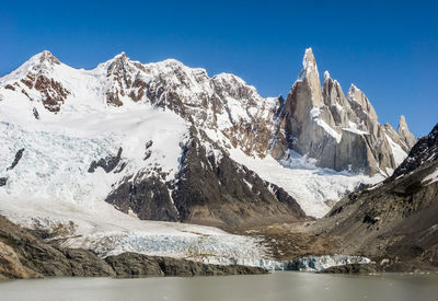 Scenic view of lake by snowcapped mountains against sky