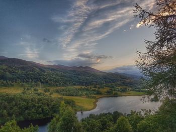 Scenic view of river by mountains against sky