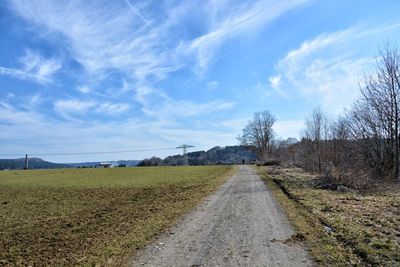 Road amidst field against sky