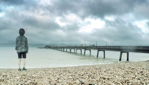 Pier on sea against cloudy sky