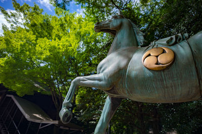Low angle view of horse statue against trees