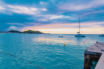 Sailboats in sea against sky during sunset