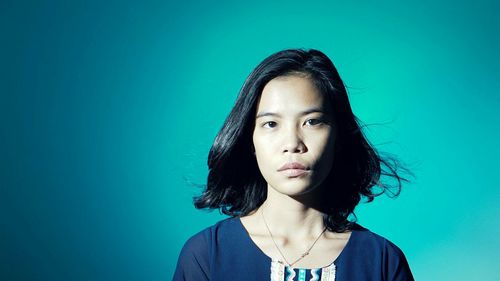 Portrait of young woman against blue background