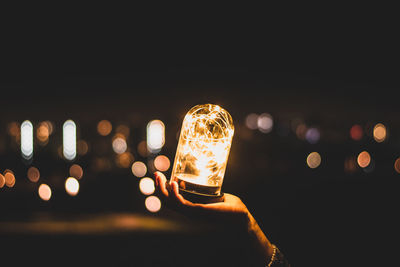 Cropped image of hand holding illuminated lighting equipment at night