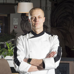 Portrait of confident chef with arms crossed standing at restaurant