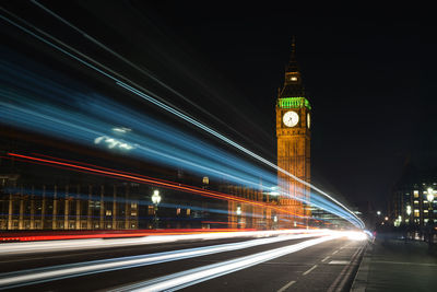 Light trails on road by big ben at night