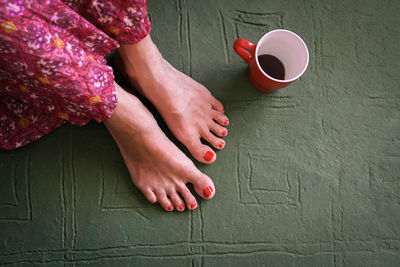 Low section of woman with cup sitting on floor