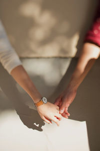 Cropped image of couple with holding hands against wall