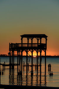 Silhouette pier on sea against clear sky during sunset