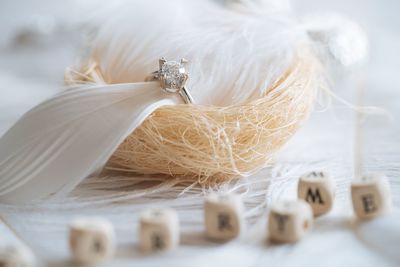 High angle view of toy blocks with wedding ring on feathers