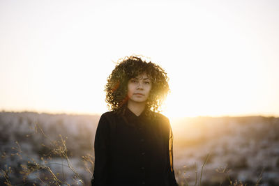 Portrait of woman standing on land against sky during sunset