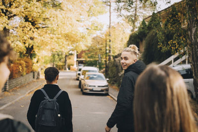 Portrait of smiling teenage boy walking with friends on street in city