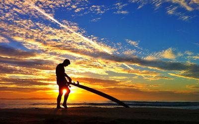 Silhouette of people on beach at sunset