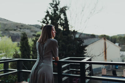 Woman standing by railing against trees