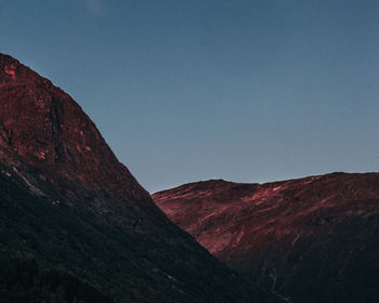 Sunset over mountain range tops and a clear blue sky