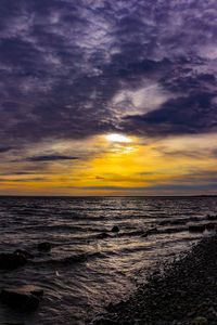 Scenic view of sea against dramatic sky during sunset