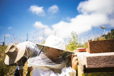 Mother working while son standing on field during sunny day