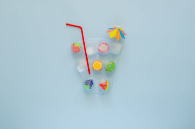 Mixed fruit drink in ice cube with red straw and cocktail umbrella. minimal summer drink concept.