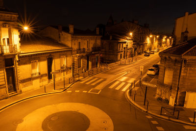 High angle view of illuminated street amidst buildings in city at night