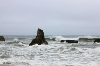 Rocks in sea against clear sky